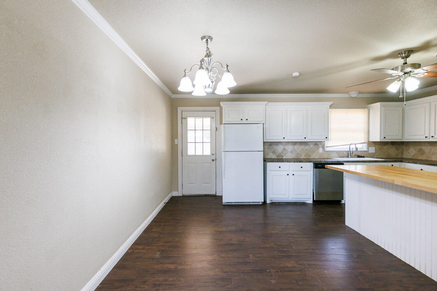 2505 52nd Street Lubbock, TX 79413 - Photo 10 of 37 a kitchen with granite countertop white cabinets a refrigerator a sink dishwasher and a stove with wooden floor