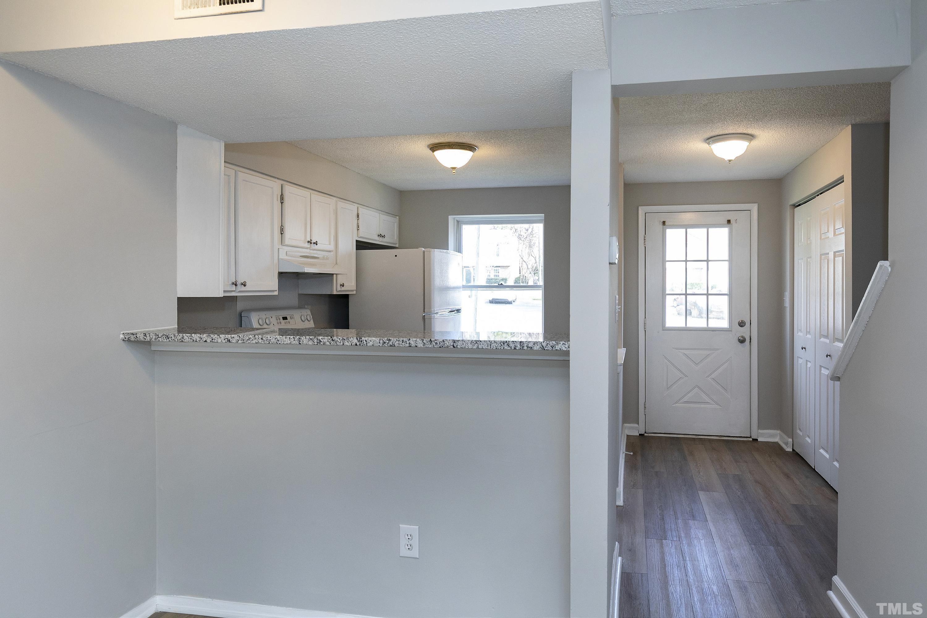 7735 Kelley Court Raleigh, NC 27615 - Photo 11 of 26 a kitchen with granite countertop a refrigerator a sink and wooden floors