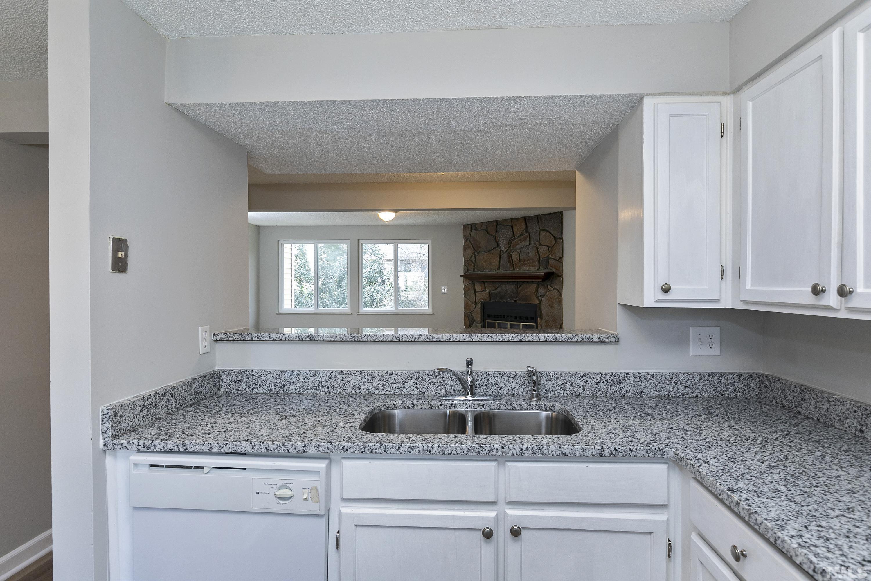 7735 Kelley Court Raleigh, NC 27615 - Photo 12 of 26 a kitchen with granite countertop a sink and white cabinets