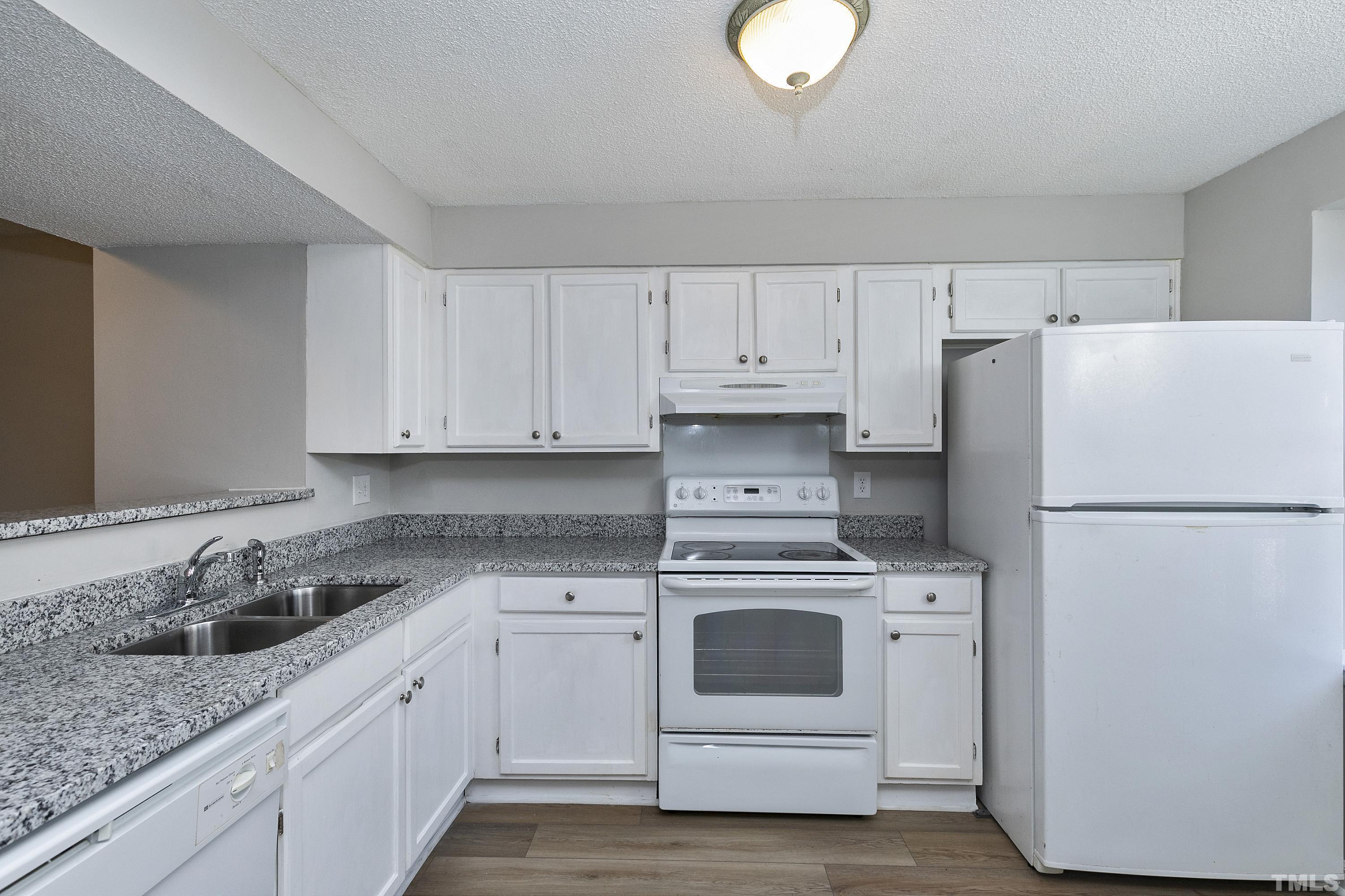 7735 Kelley Court Raleigh, NC 27615 - Photo 3 of 26 a kitchen with white cabinets and white appliances