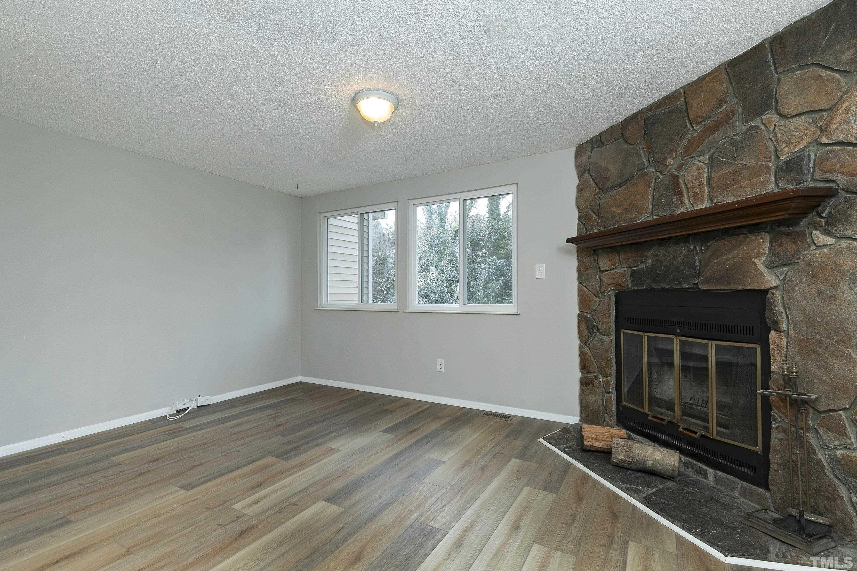 7735 Kelley Court Raleigh, NC 27615 - Photo 7 of 26 a view of an empty room with wooden floor and a fireplace