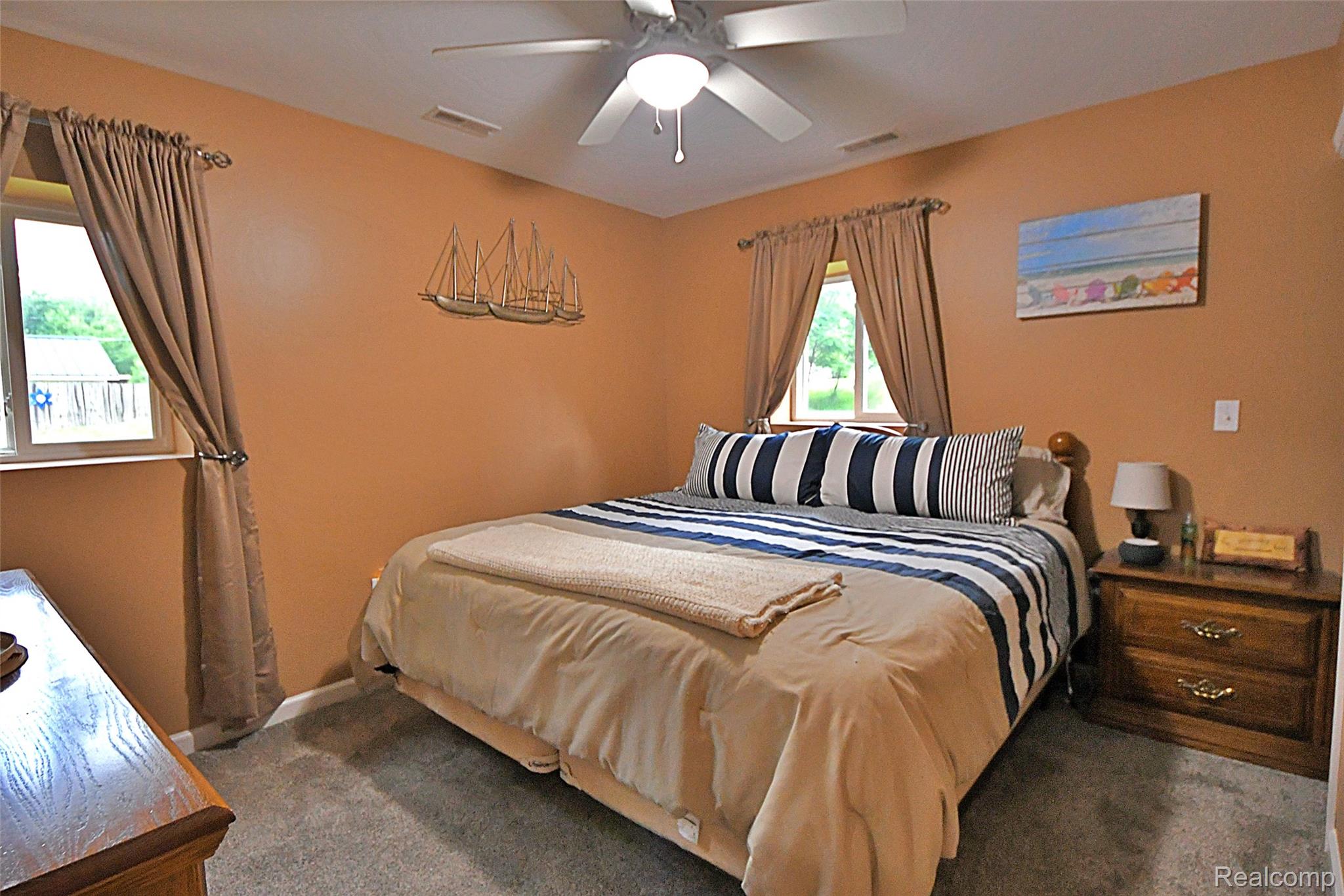 9611 Monroe Road St. Helen, MI 48656 - Photo 13 of 24 Bedroom featuring neutral-toned walls, gray carpet flooring, and two windows with drapes