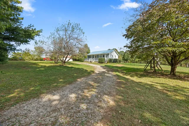 a view of a big house with a big yard and large trees