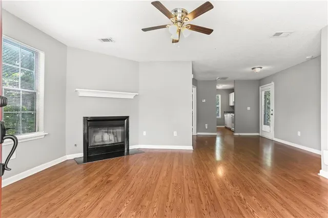 a view of a livingroom with a fireplace a ceiling fan and wooden floor