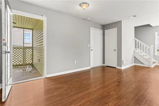 a view of an empty room with wooden floor and a window