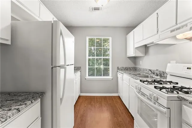 a kitchen with a stove a refrigerator and a white cabinets