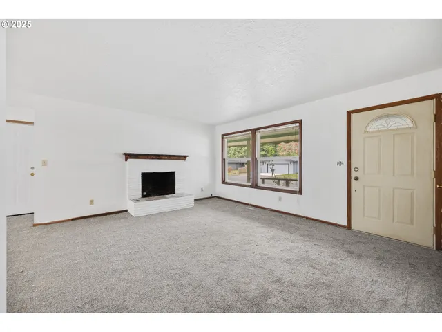 a view of an empty room with a fireplace and a window
