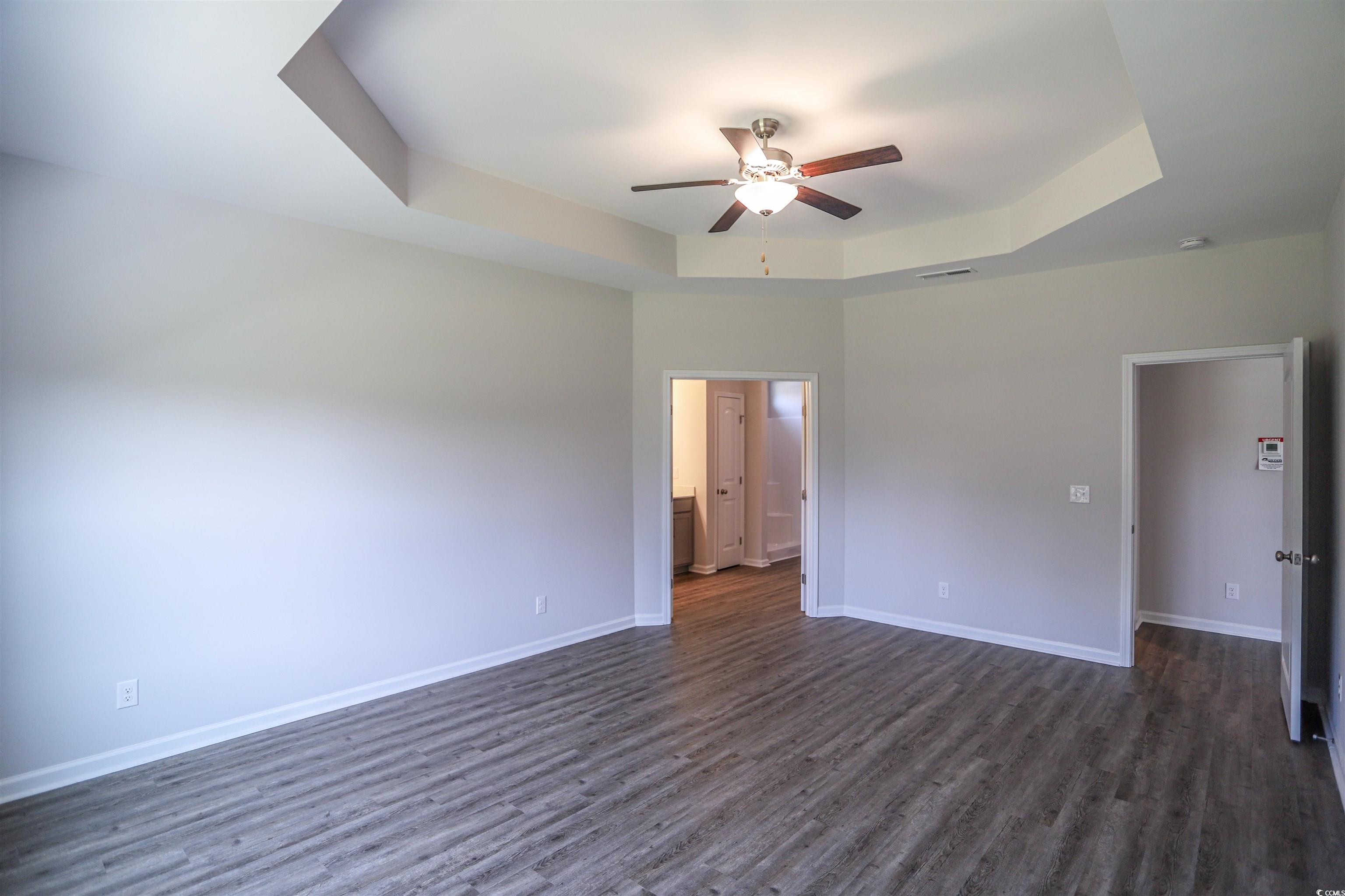 611 Bay Street Aynor, SC 29544 - Photo 4 of 12 Unfurnished bedroom with a raised ceiling, dark wood-style floors, ceiling fan, and ensuite bathroom