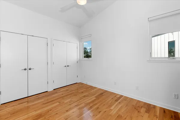 a view of empty room with wooden floor and fan
