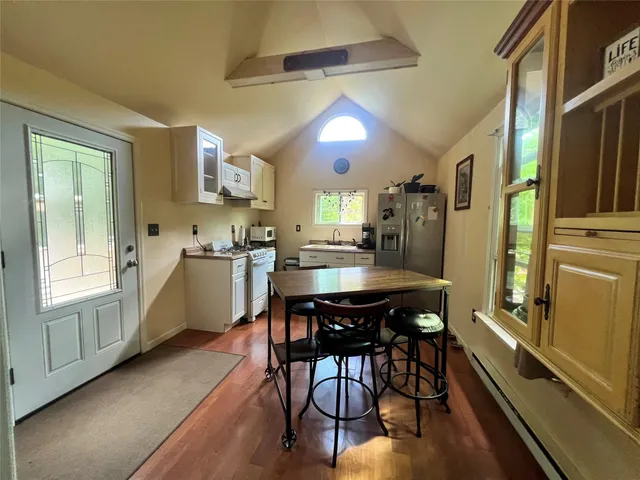 a kitchen with stainless steel appliances kitchen island granite countertop a table chairs sink and cabinets