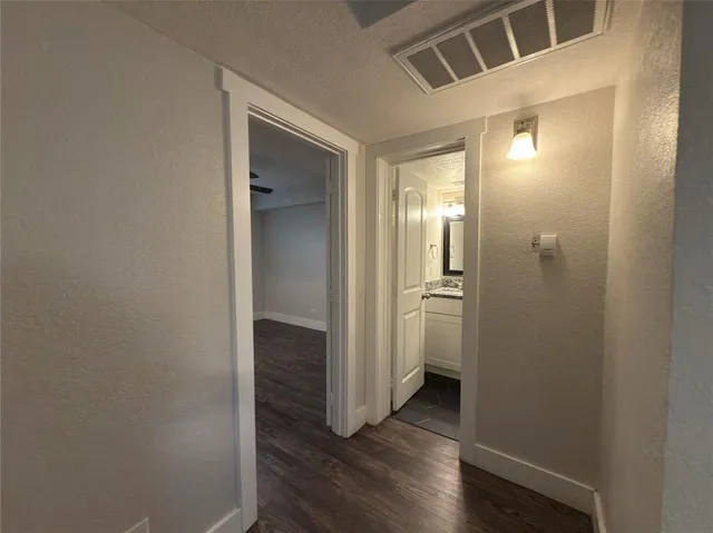 a view of a hallway with wooden floor and a bathroom