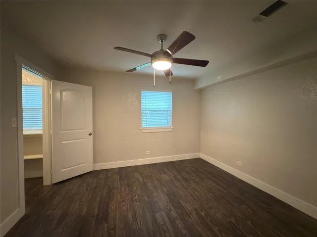 a view of an empty room with wooden floor closet and a window