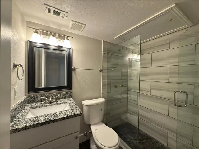 a bathroom with a granite countertop sink toilet and shower