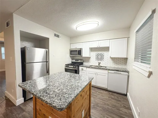 a kitchen with stainless steel appliances granite countertop a sink stove refrigerator and cabinets