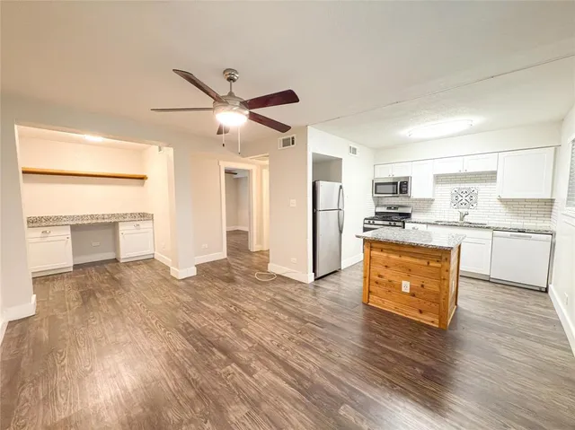 a view of kitchen with microwave a stove and white cabinets