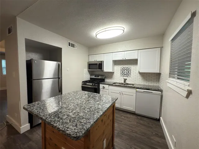 a kitchen with stainless steel appliances granite countertop a sink stove refrigerator and cabinets