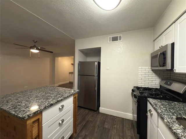 a kitchen with granite countertop a refrigerator and a stove
