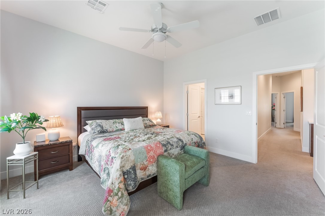 6432 Spring Jog Street Las Vegas, NV 89166 - Photo 18 of 61 A well-lit primary bedroom featuring a vaulted ceiling and soft, neutral carpet.