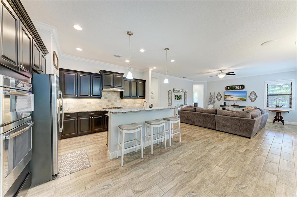 12642 Harney Street Venice, FL 34293 - Photo 13 of 85 a kitchen with stainless steel appliances kitchen island granite countertop a stove top oven a sink a dining table and chairs