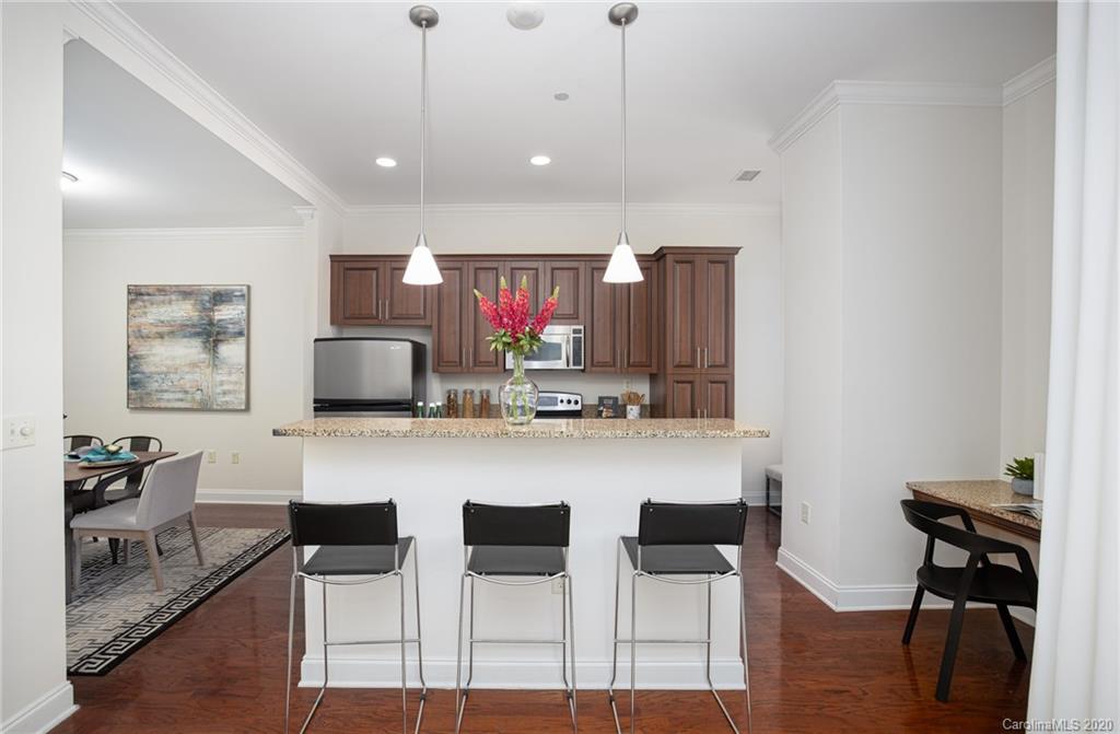 230 South Tryon Street, Unit 305 Charlotte, NC 28202 - Photo 16 of 32 a kitchen with a dining table chairs and a refrigerator
