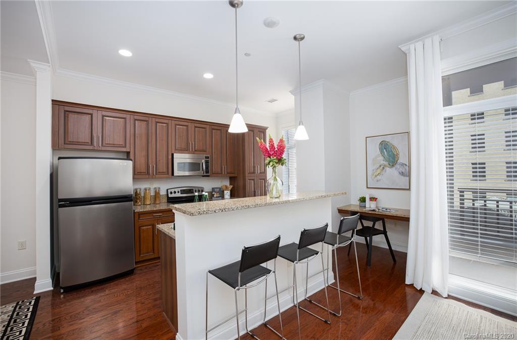 230 South Tryon Street, Unit 305 Charlotte, NC 28202 - Photo 17 of 32 a kitchen with stainless steel appliances granite countertop a refrigerator a sink dishwasher a stove and a refrigerator with wooden floor