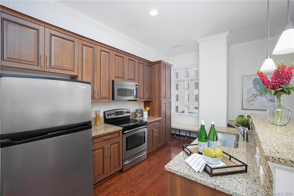 230 South Tryon Street, Unit 305 Charlotte, NC 28202 - Photo 18 of 32 a kitchen with stainless steel appliances granite countertop a refrigerator a stove a sink dishwasher and white cabinets with wooden floor