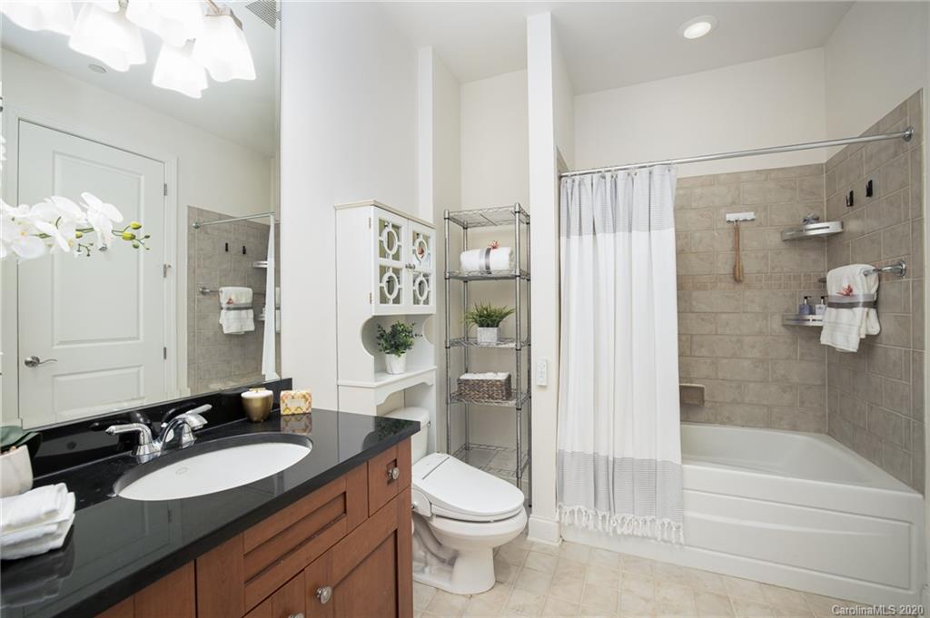 230 South Tryon Street, Unit 305 Charlotte, NC 28202 - Photo 28 of 32 a bathroom with a granite countertop sink toilet a large mirror a shower and a bathtub