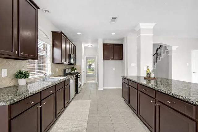 a kitchen with stainless steel appliances granite countertop a sink counter space cabinets and a large window