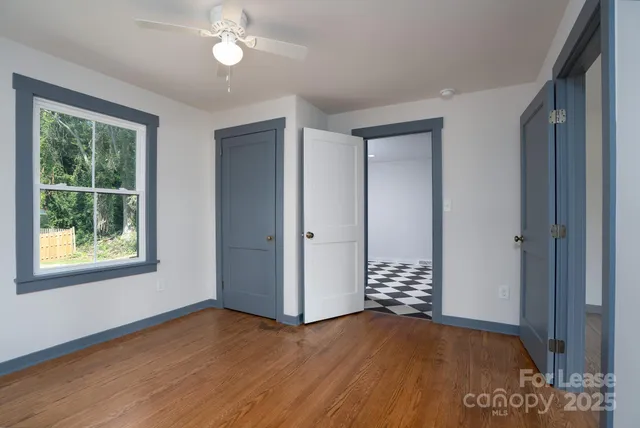 a view of an empty room with window and wooden floor