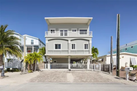 a view of a white building among the street with palm trees