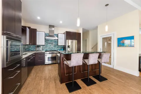 a large kitchen with stainless steel appliances granite countertop a stove a sink dishwasher a dining table and chairs with wooden floor