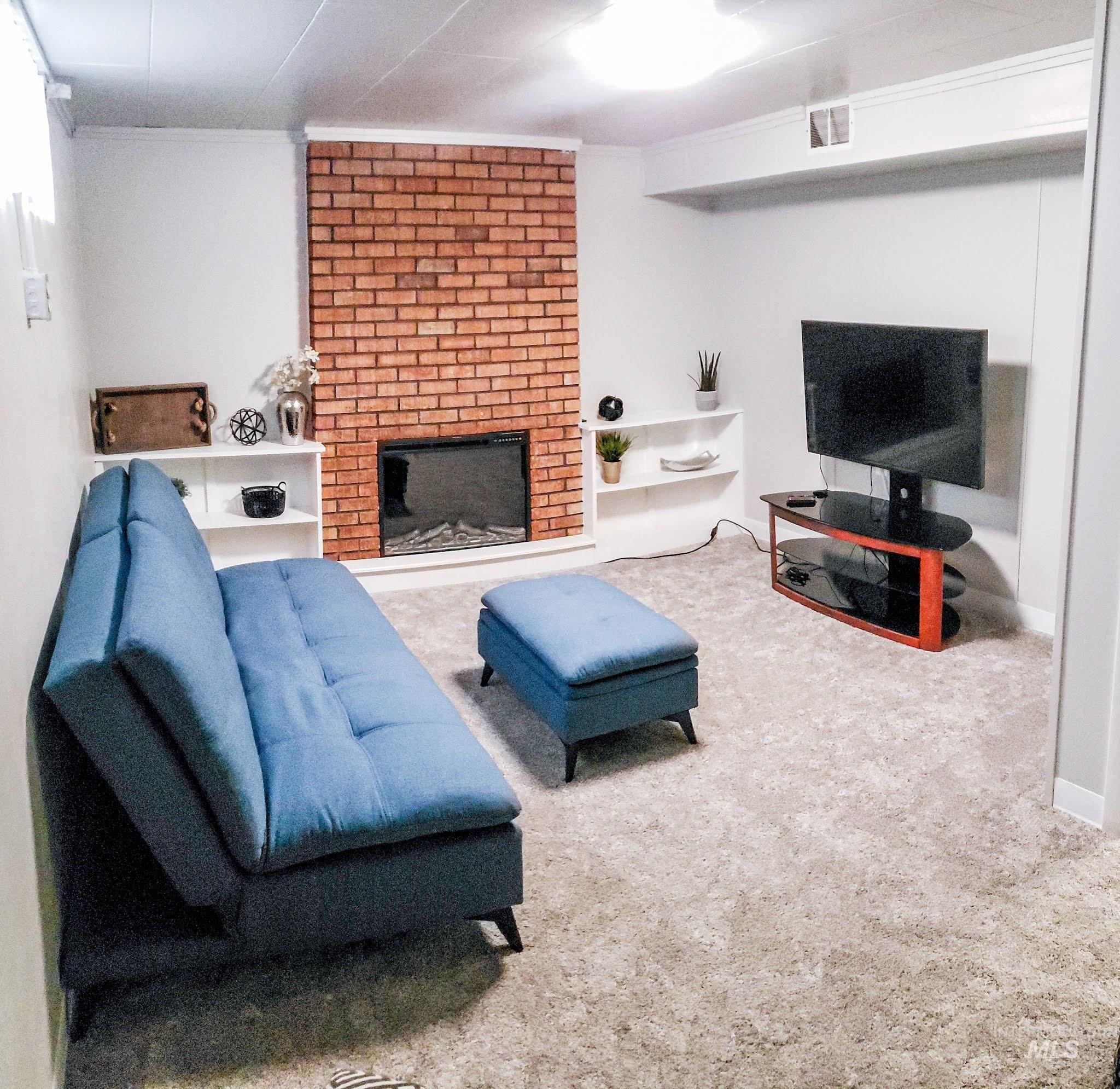 814 Baker Street Boise, ID 83706 - Photo 11 of 26 Living space featuring a brick-accented fireplace with electric insert, built-in shelving, light-toned carpeting, and recessed ceiling lighting