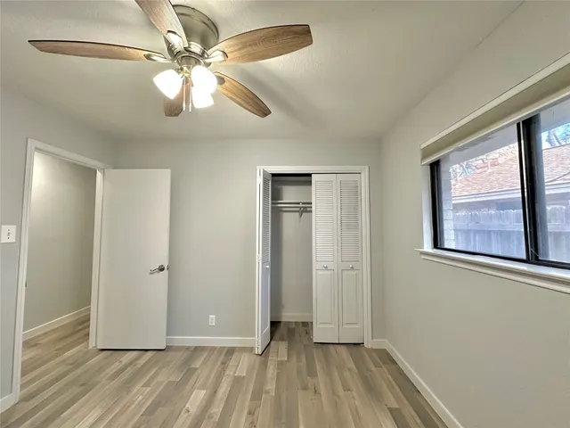 a view of an empty room with window and wooden floor
