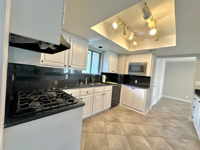 a kitchen with granite countertop a sink stainless steel appliances and white cabinets