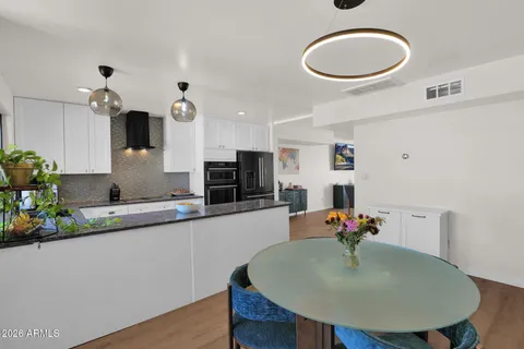 a kitchen with stainless steel appliances granite countertop a sink a stove a refrigerator cabinets and dining table