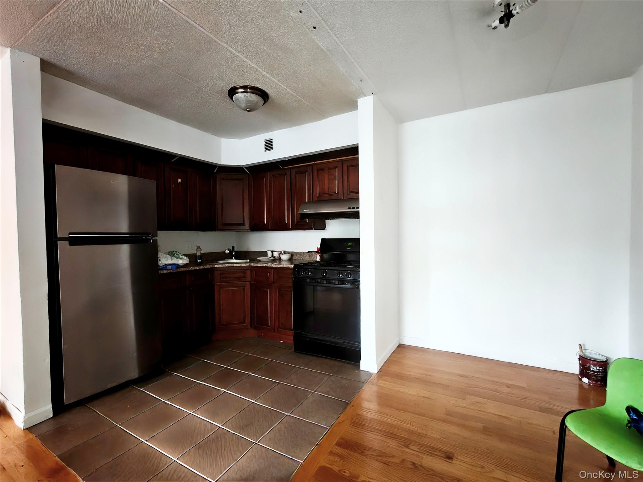 134-46 Maple Avenue, Unit 1C Queens, NY 11355 - Photo 11 of 12 a kitchen with a refrigerator a microwave oven and a sink with wooden floor