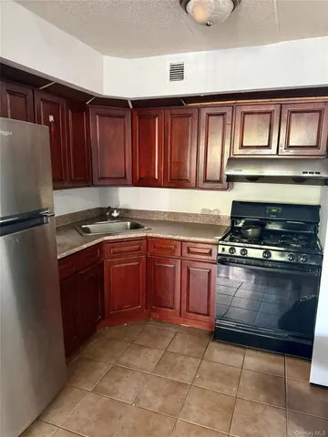 a kitchen with granite countertop a refrigerator and a stove top oven