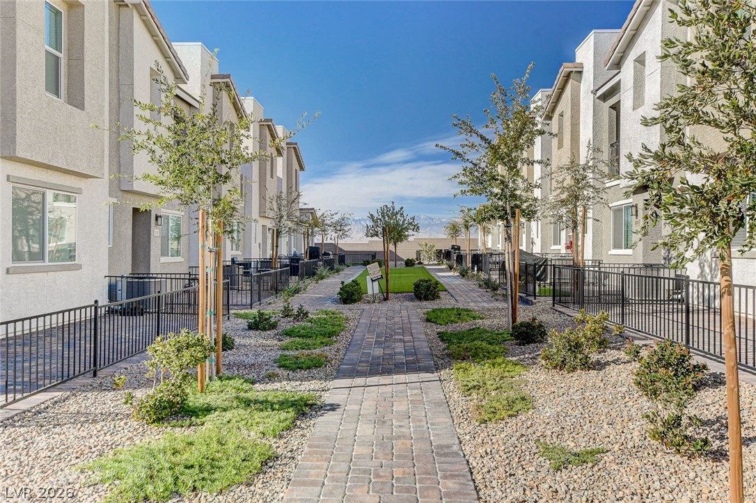 6924 Spicy Merlot Street North Las Vegas, NV 89086 - Photo 41 of 83 A well-manicured courtyard with a paver pathway divides modern townhomes, creating an inviting community space.