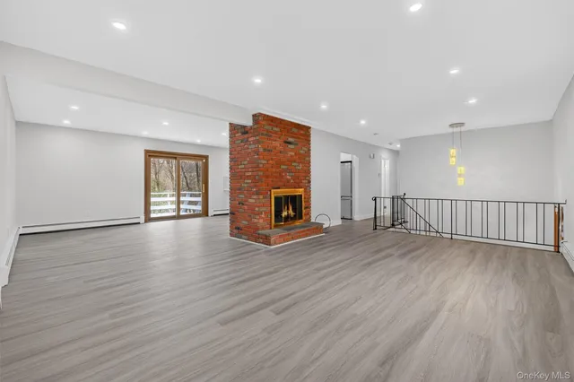 a view of an empty room with wooden floor fireplace and a window