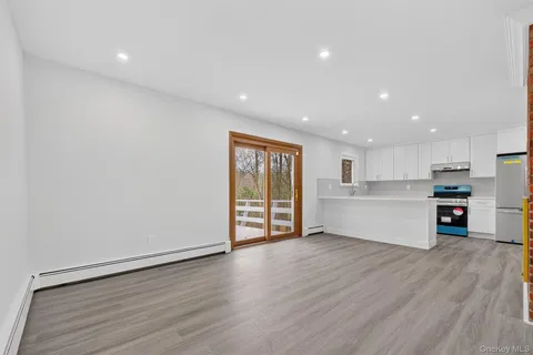 a view of an empty room with wooden floor and kitchen