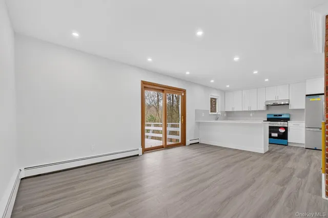 a view of an empty room with wooden floor and kitchen