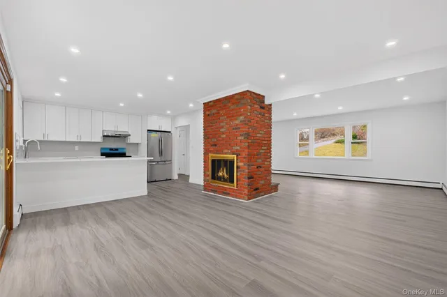 a view of an empty room with a window and wooden floor