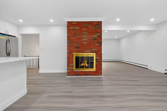 a view of an empty room with wooden floor fireplace and a window
