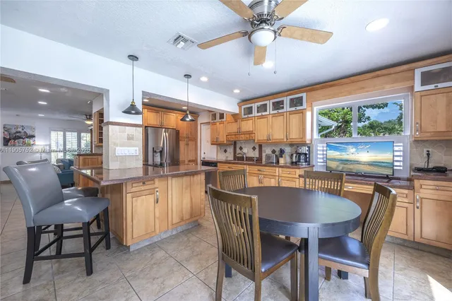 a kitchen with stainless steel appliances granite countertop a stove a refrigerator a kitchen island a table and chairs