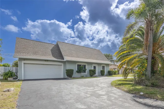a front view of a house with a garden and trees