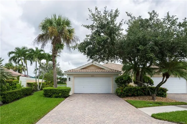 a front view of a house with a garden and tree