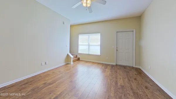 a view of a big room with windows and chandelier fan