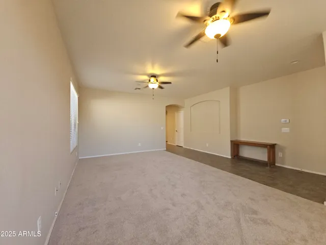 a view of an empty room with a chandelier fan