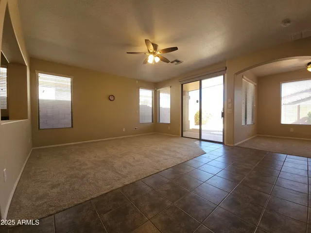 a view of an empty room with window and chandelier fan