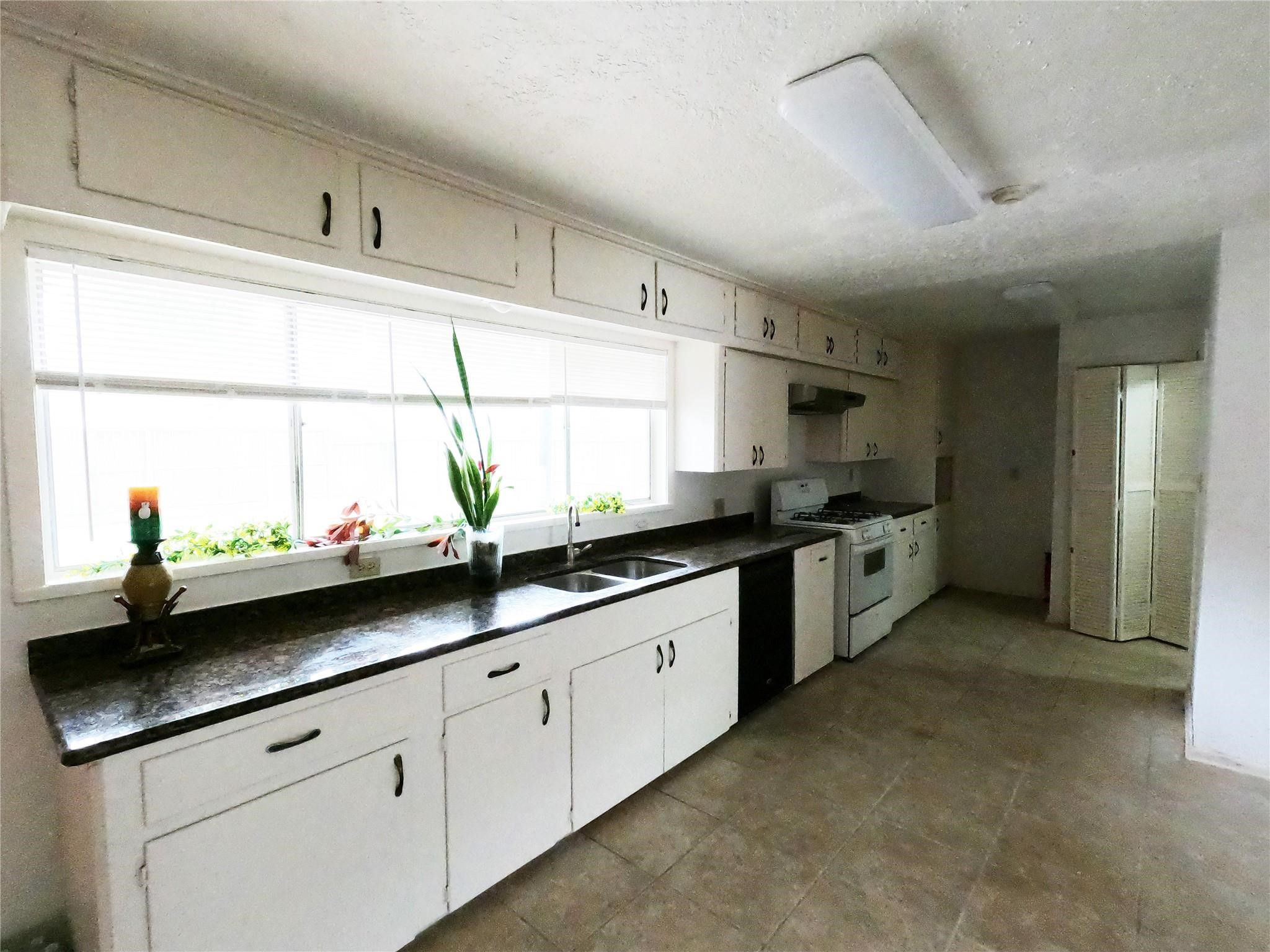 5231 Beechnut Street Houston, TX 77096 - Photo 13 of 19 a kitchen with sink a window and cabinets